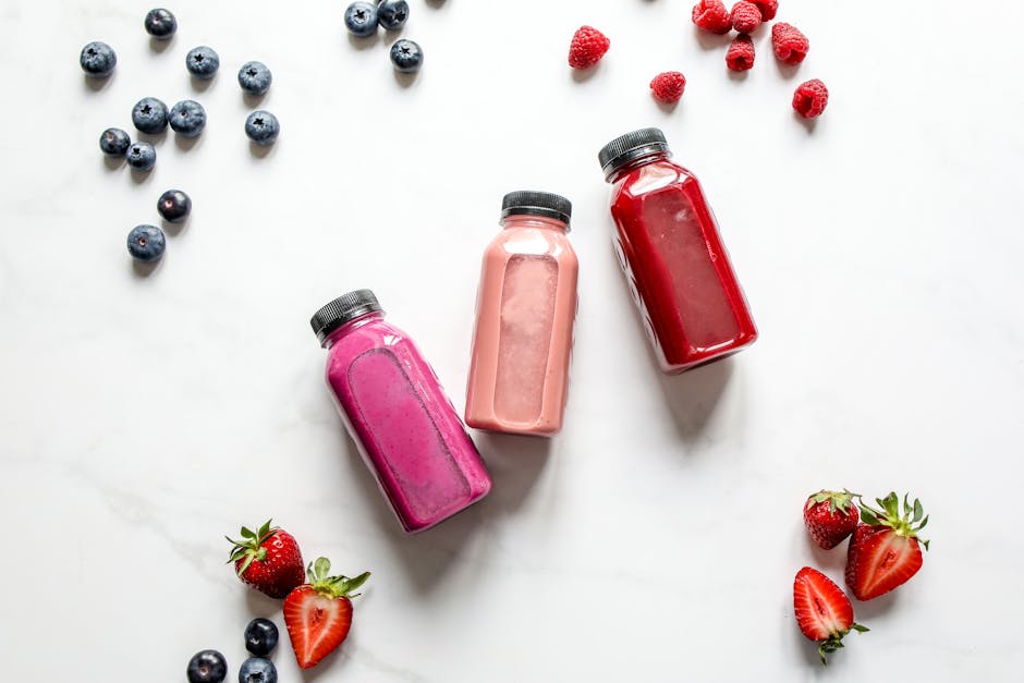 Colorful breakfast smoothies in glasses with fresh fruit toppings.