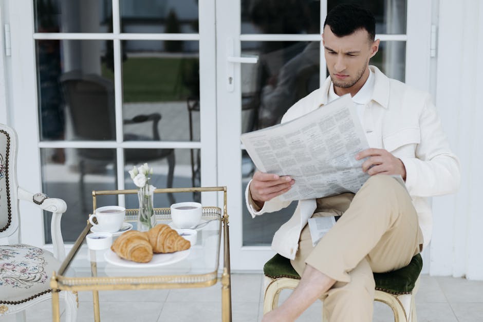 Hands turning pages of a food magazine beside a cup of coffee.