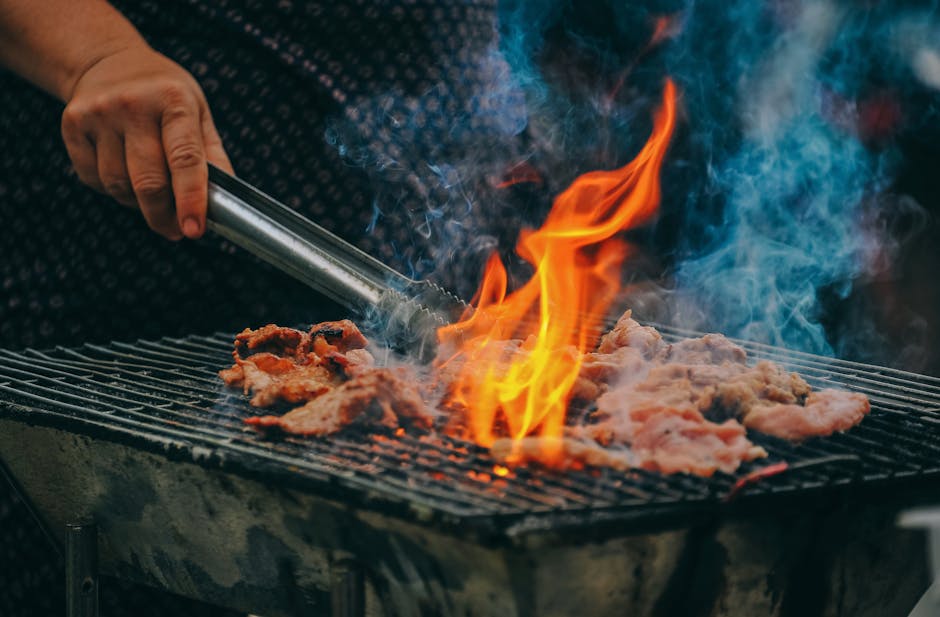 Meat and vegetables grilling over hot coals on an outdoor grill.