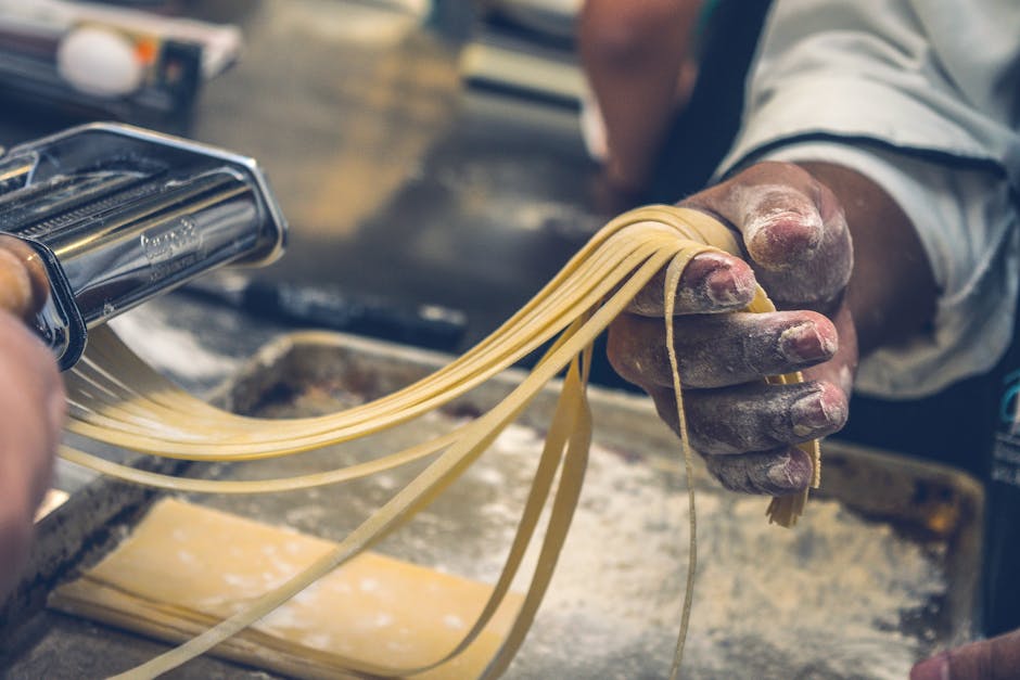 Fresh homemade pasta being made on a floured wooden surface.